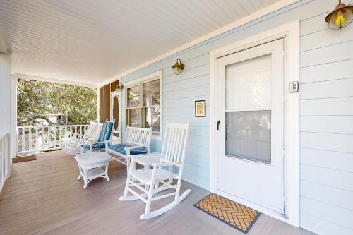 a porch with white chairs and a door at Pelican Bay 46 in Isle of Palms