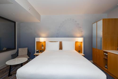 a bedroom with a large bed and a chair at DoubleTree by Hilton Hotel London - Tower of London in London