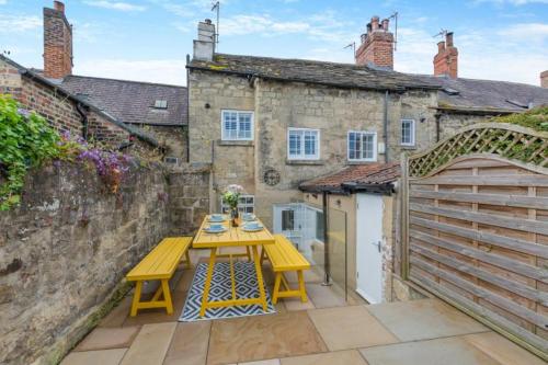 a yellow table on a patio in front of a building at Castle Yard Cottage in Knaresborough