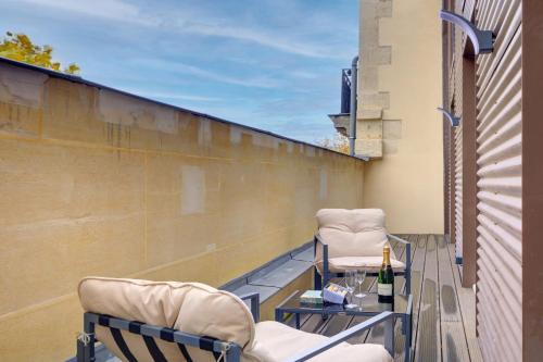 - un balcon avec 2 chaises et une bouteille de champagne dans l'établissement Bluestay 294 - Superbe appartement à Paris 17, à Paris