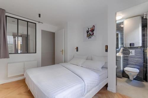 - une chambre blanche avec un grand lit et des toilettes dans l'établissement MyKeypers - Stylish & Luxury Duplex 2BR-8P - Le Marais, à Paris