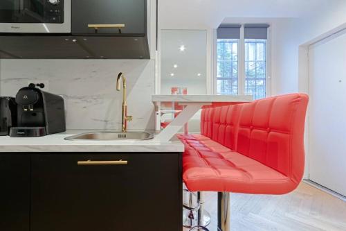 une cuisine avec un comptoir et un tabouret de bar rouge dans l'établissement MyKeypers - Stylish & Luxury Duplex 2BR-8P - Le Marais, à Paris