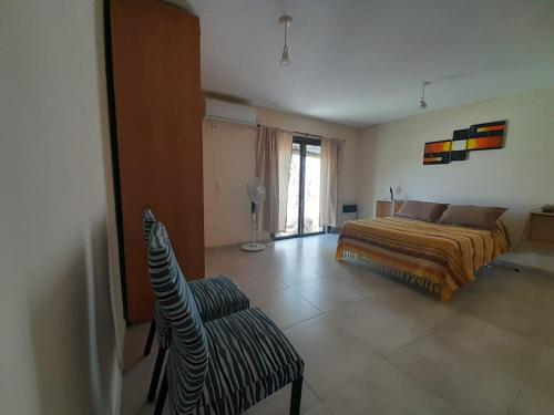 een slaapkamer met een bed en een stoel erin bij Casa El Almendro-Barrio Privado - Para 2 personas in Ciudad Lujan de Cuyo