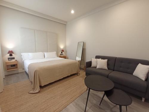 a hotel room with a bed and a couch at Uma Suites Parada del Marqués in Seville