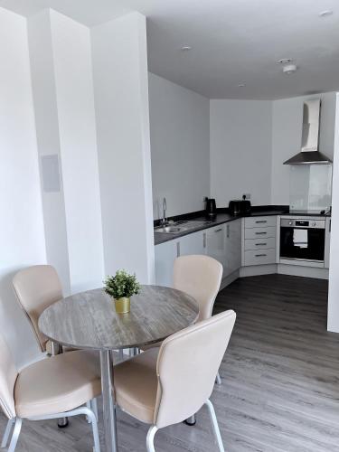 a dining room with a table and chairs in a kitchen at Ascot House Apartments in Peterborough