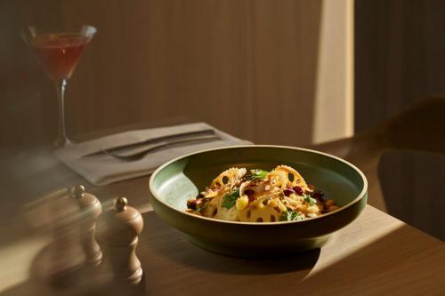 a bowl of pasta on a table with a glass of wine at Holiday Inn & Suites Vientiane by IHG in Vientiane