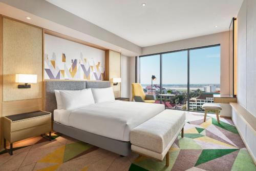 a bedroom with a large bed and a large window at Holiday Inn & Suites Vientiane by IHG in Vientiane