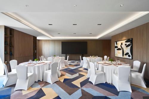 a conference room with white tables and chairs and a screen at Holiday Inn & Suites Vientiane by IHG in Vientiane
