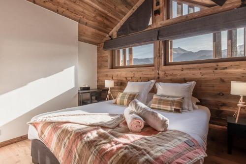 - une chambre avec un grand lit, des murs en bois et des fenêtres dans l'établissement Chalet Remy - Chalet de luxe - Montagnes de Saint Gervais, à Saint-Gervais-les-Bains