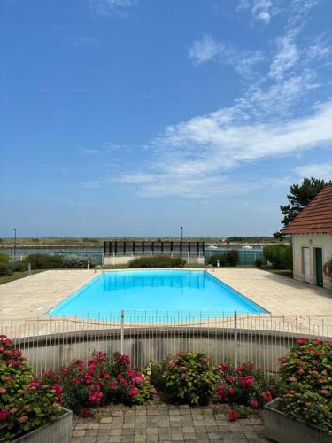 - une grande piscine dans une cour fleurie dans l'établissement Ravissante maison en bord de mer, à Dives-sur-Mer