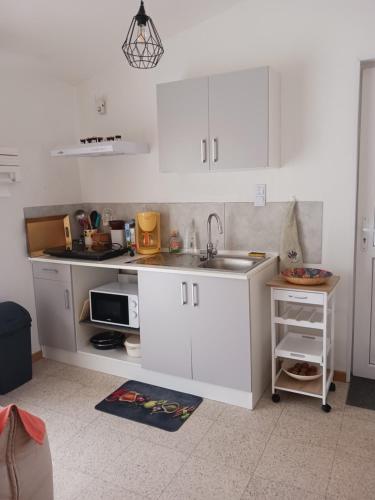 une cuisine avec des armoires blanches et un évier dans l'établissement Le p'tit chez nous au Galajou, à Carsac-Aillac