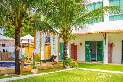 a house with two palm trees and a swimming pool at Pousada De Bona Studio's in Pôrto de Pedras