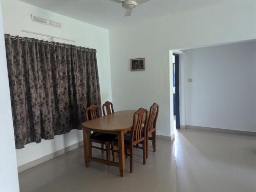 a wooden table and chairs in a room at Indeevaram Apartments in Kovalam