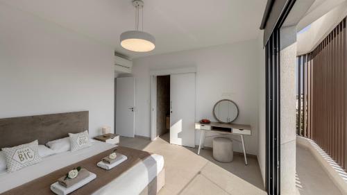 a white bedroom with a large bed and a mirror at Nissi Residences Villa 4 in Ayia Napa