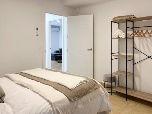 Un dormitorio blanco con una cama y un espejo. en TAYP San Marcos 102, en Talayuela