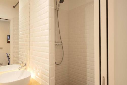 une salle de bain blanche avec une douche et un lavabo dans l'établissement MyKeypers - Cozy Studio near Canal Saint Martin, à Paris