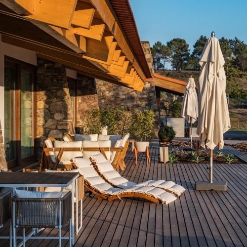 a patio with a bunch of chairs and an umbrella at TEIMA, Alentejo SW in São Teotónio