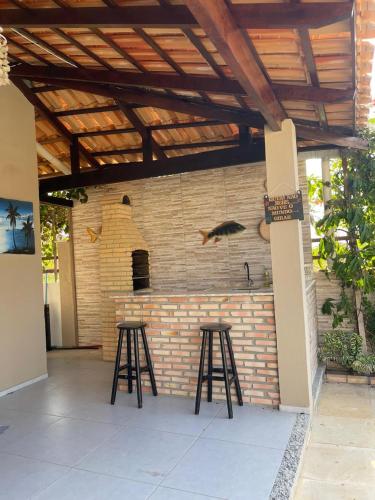 a patio with two stools and a brick wall at Casa Atlantico Flecheiras in Trairi