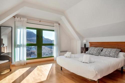 a bedroom with a large bed and a large window at Argualas - Triplex con piscina - By CARDI Suites in Panticosa