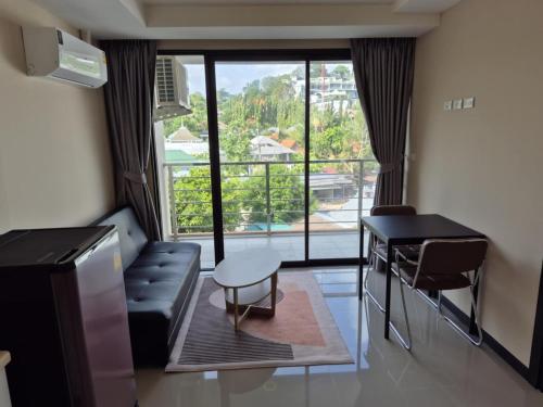 a living room with a couch and a table and a window at Rawai beach condominium 拉薇海滩酒店公寓 in Nai Harn Beach