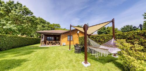 a house with a hammock in the yard at Effect Algara Beach Resort - Ultra All Inclusive and Free Parking in Kranevo
