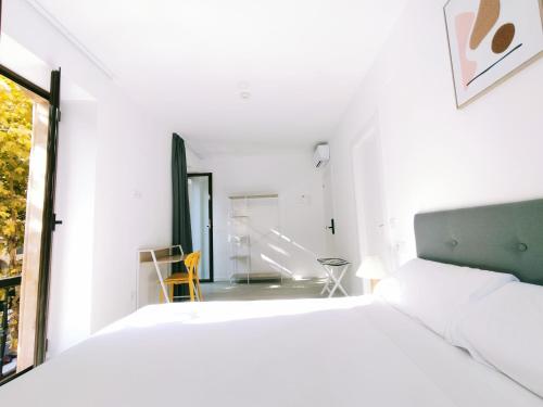 a white bedroom with a bed and a window at Hotel Gran Vía by gaiarooms in Salamanca