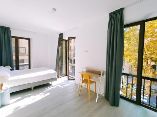 a bedroom with a bed and a desk and windows at Hotel Gran Vía by gaiarooms in Salamanca