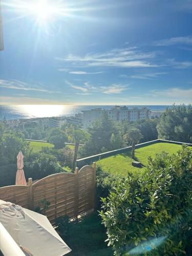 a garden with a fence and a view of a city at Appartement lumineux Vue Mer, Piscine et tennis in Nice