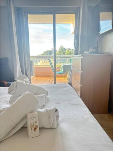 a bedroom with towels on a bed with a balcony at Appartement lumineux Vue Mer, Piscine et tennis in Nice