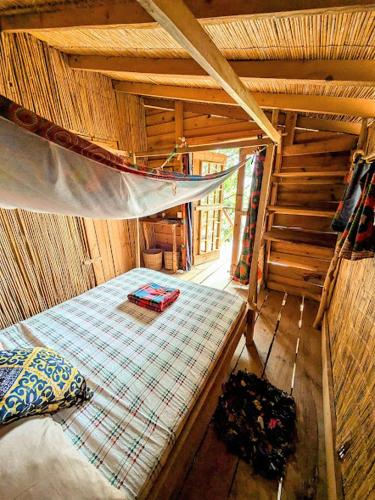a room with a bed and a hammock in a cabin at Butterfly Space- A Non-Profit Eco-Lodge in Nkhata Bay