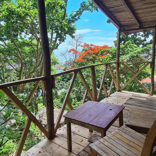 a wooden bench sitting on a wooden deck with trees at Butterfly Space- A Non-Profit Eco-Lodge in Nkhata Bay