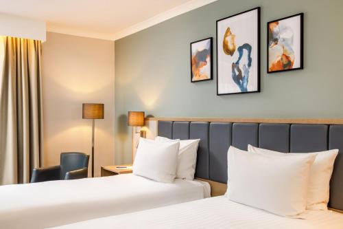 a hotel room with two beds and a chair at Delta Hotels by Marriott Milton Keynes in Milton Keynes