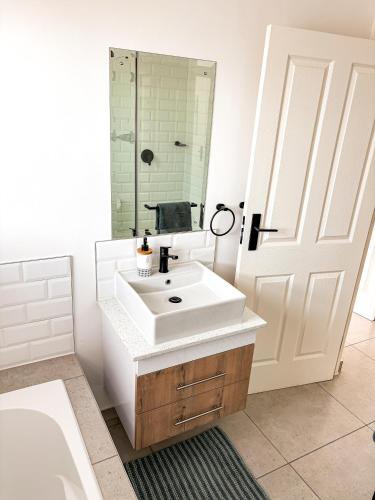 a bathroom with a white sink and a mirror at 21 On the Green in Stompneusbaai