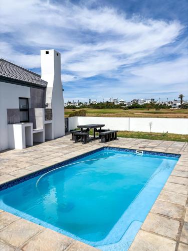 a swimming pool with a table and a picnic table at 21 On the Green in Stompneusbaai