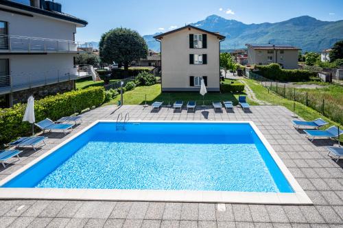 a swimming pool with chairs and a house in the background at My Holidays New Eden in Domaso