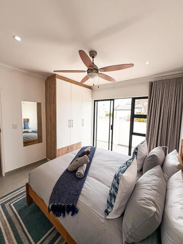 a bedroom with a large bed with a ceiling fan at 21 On the Green in Stompneusbaai