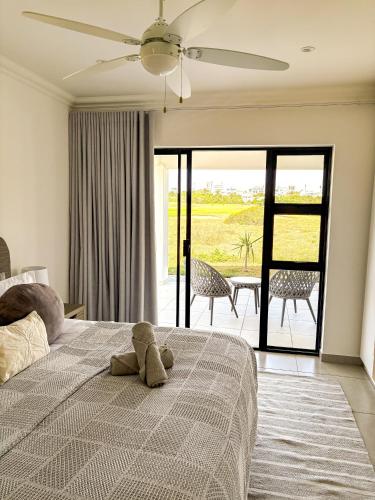 a teddy bear sitting on a bed in a bedroom at 21 On the Green in Stompneusbaai