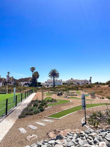 a park with a pathway and palm trees and houses at 21 On the Green in Stompneusbaai