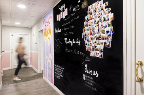 a person walking down a hallway with a wall with pictures at Best Western Hotel Lakmi Nice in Nice