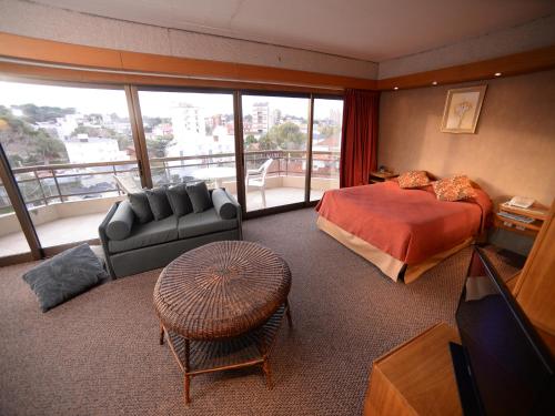Habitación de hotel con cama, sofá y TV en Hostería Tequendama Classic & Resort en Villa Gesell