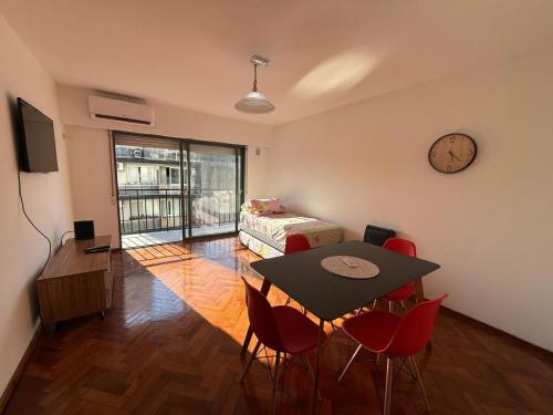 a room with a table and a bed and a clock at Aloha II in Rosario