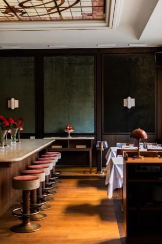 a dining room with a long table and stools at Parkhotel Mondschein, a Member of Design Hotels in Bolzano