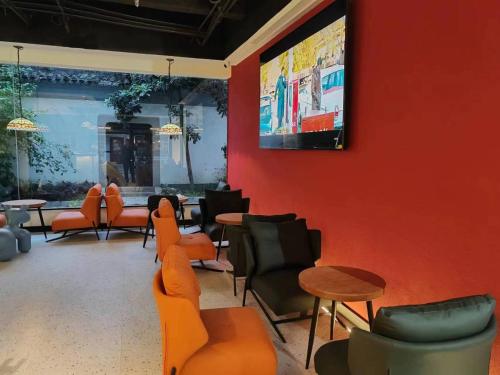 a waiting room with orange chairs and tables and a tv at 不负韶华青年旅馆 Youth Hostel in Suzhou