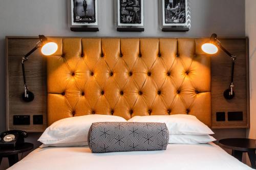 a bed with a large orange headboard and two lights at Abbey Hotel Bath, a Tribute Portfolio Hotel in Bath
