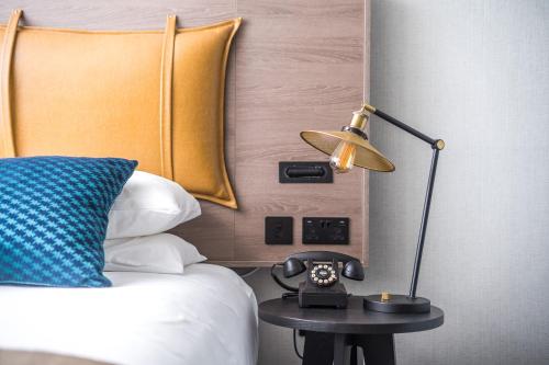 a bed with a lamp and a phone on a table at Abbey Hotel Bath, a Tribute Portfolio Hotel in Bath