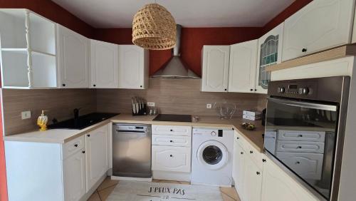 une cuisine avec des armoires blanches et une laveuse et une sécheuse dans l'établissement Le Clos de la Treille, à Épernay