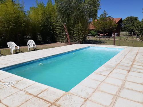 a swimming pool with two chairs in a yard at Complejo La Morena in Mina Clavero