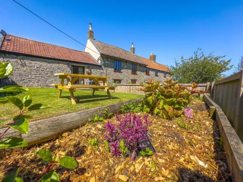 a garden with a bench and flowers in front of a house at Cosy Coastal Retreat-Dog Friendly in Worle