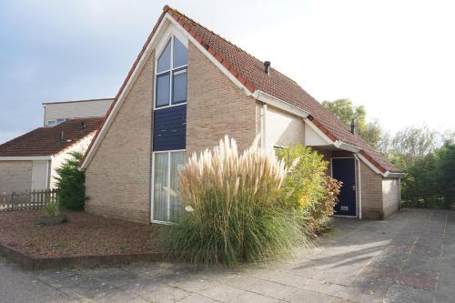 a brick house with a window and a bush at Kustverhuur, Breskens Zwin 089 in Breskens