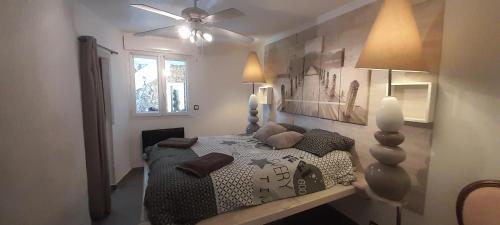 une chambre avec un lit et un ventilateur de plafond dans l'établissement Villa Romana, à La Garonnette-Plage